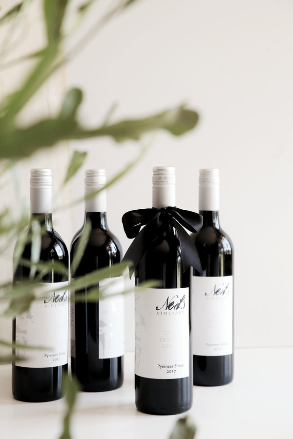 Australian Red Wine bottles of Shiraz standing with eucalyptus leaves in the front. White clean labels with silver branding.