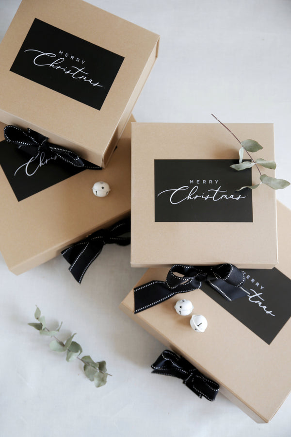 Christmas Hampers say it with a box with black bows and merry Christmas on the top of the box in black and white luxury printing